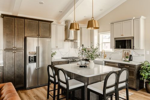 Kitchen with white cabinetry, marble backsplash, dark lower cabinets and a farmhouse sink