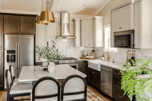 Kitchen farmhouse sink with a gold gooseneck faucet and marble slab backsplash