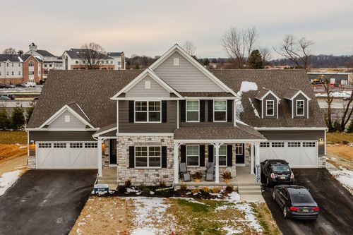 Aerial view of a large two-story custom home with multiple garage bays and a snow-dusted driveway
