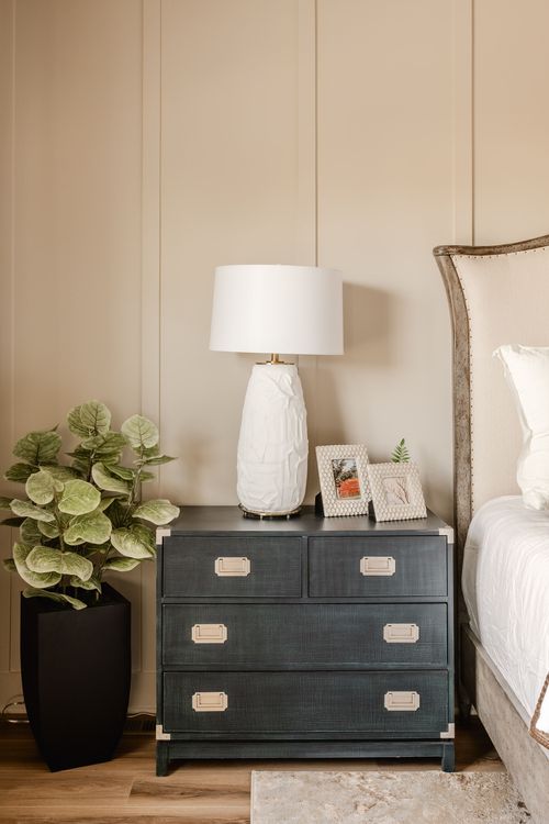 Bedroom dresser styled with a white ceramic lamp and framed photos
