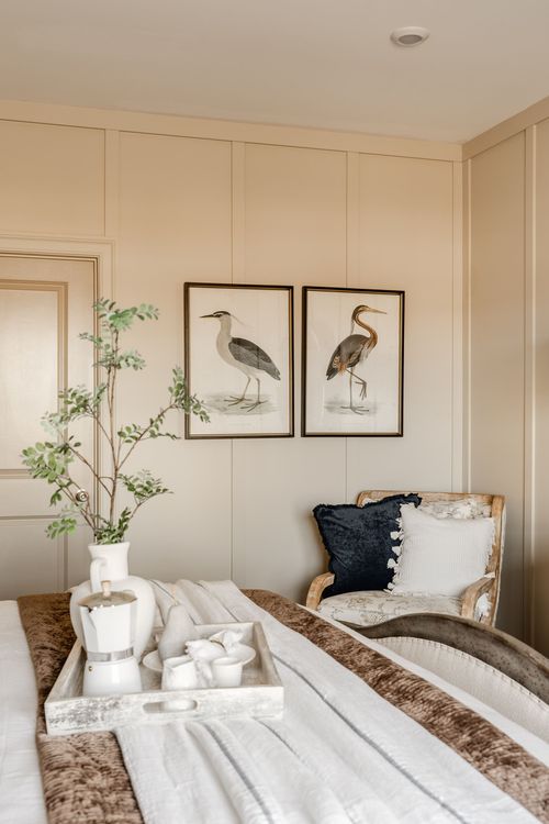 Bedroom corner with heron artwork, a cozy accent chair and a breakfast tray on the bed