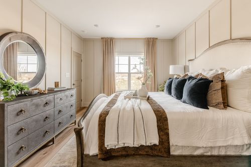 Bedroom with a round mirror, gray dresser and patterned bedding
