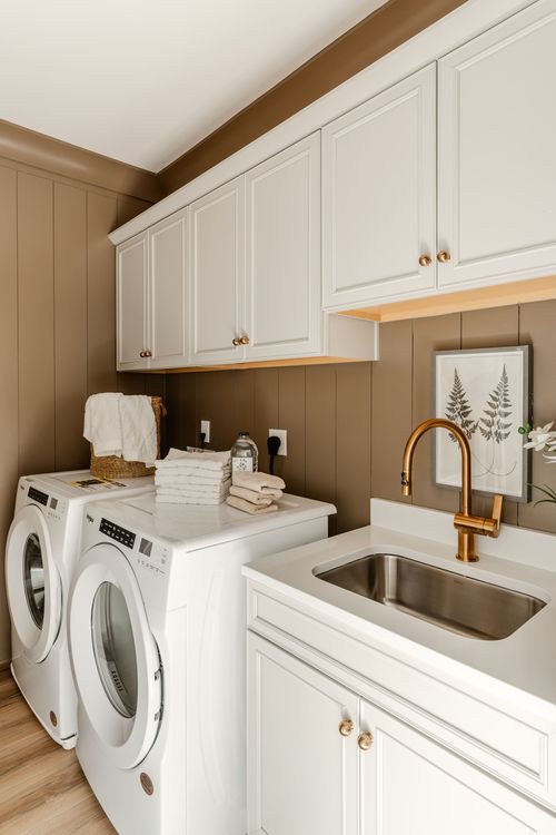 Laundry room with white cabinetry, front-load washer and dryer, and a folding counter with sink