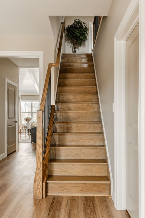 Wood staircase with a mixed wood and metal railing overlooking the living room below