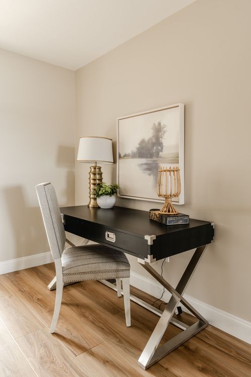 Small office nook with a black desk, upholstered chair and framed landscape art