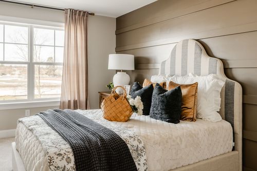 Bedroom with a shiplap accent wall, striped headboard and layered rust and navy pillows