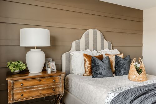 Striped headboard bed with rust and navy velvet pillows against a shiplap wall