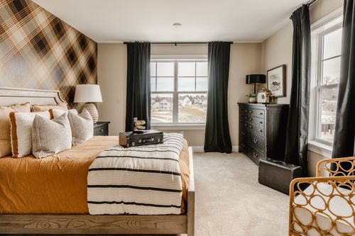 Bedroom with a dark plaid accent wall, rust bedding and black nightstands