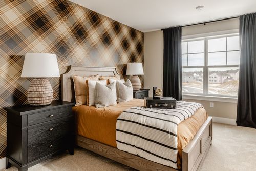 Bedroom with plaid wallpaper, an upholstered headboard and warm rust-toned bedding