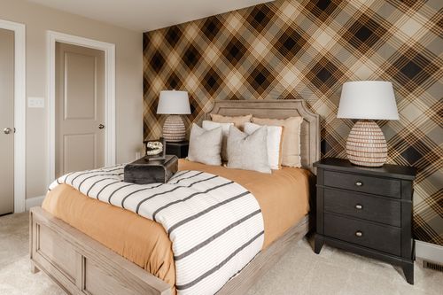 Bedroom with plaid wallpaper, closet doors and a bed dressed in rust-toned bedding