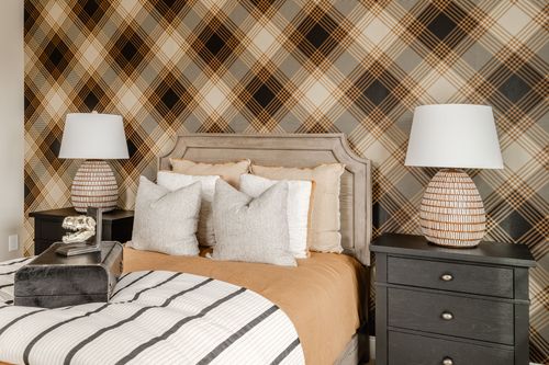 Bedroom with plaid wallpaper flanked by matching lamps on black nightstands
