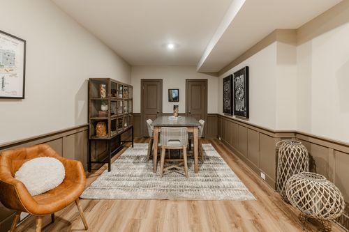 Basement flex room with a leather accent chair, wainscoting and a round dining table