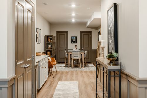 Hallway with a glossy paneled door, runner rug and a staircase leading to the lower level