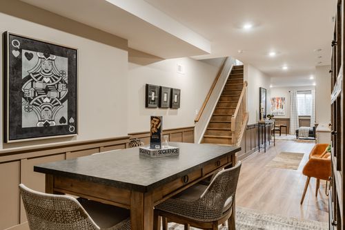 Game room area with framed card-themed art, a staircase and a glimpse of the wet bar beyond