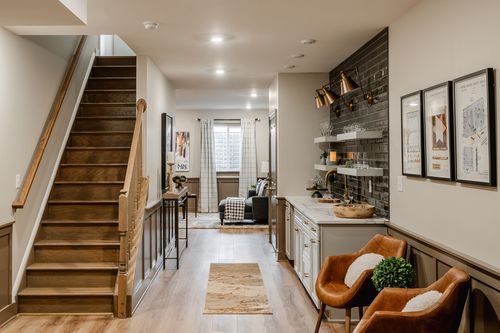 Basement living area with a wood staircase, wet bar and leather lounge chairs