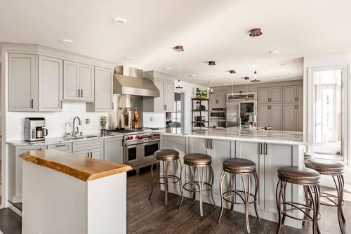 White kitchen with stainless appliances, a live-edge wood breakfast bar and pendant lighting