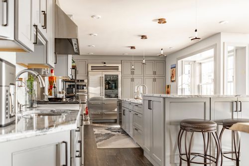 Kitchen with stainless refrigerator, gray cabinets, dark hardwood floors and patterned runner rug