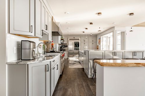 Kitchen with double wall ovens, live-edge wood island counter and dark hardwood floors