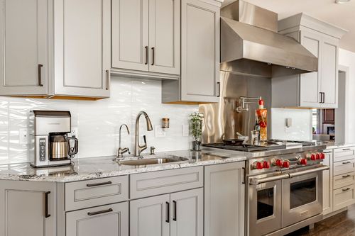 Kitchen with coffee station, white tile backsplash and red-knobbed gas range