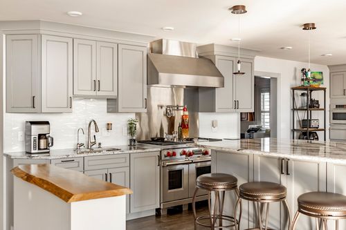 Kitchen with a stainless range and hood, open shelving and a live-edge wood counter with bar stools