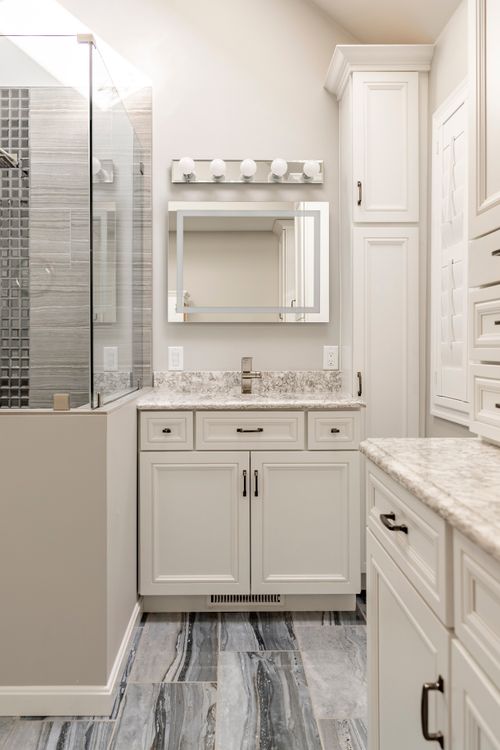 Bathroom with glass shower, white cabinetry and wood-framed shuttered window