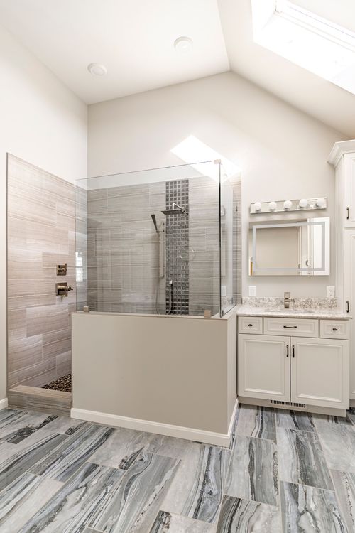 Walk-in shower with mosaic tile column, pebble floor and dual vanity area