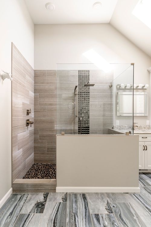 Walk-in shower with mosaic tile accent, pebble floor and skylight above