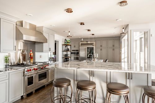 Gray kitchen with glass-front display cabinetry and a live-edge wood bar counter