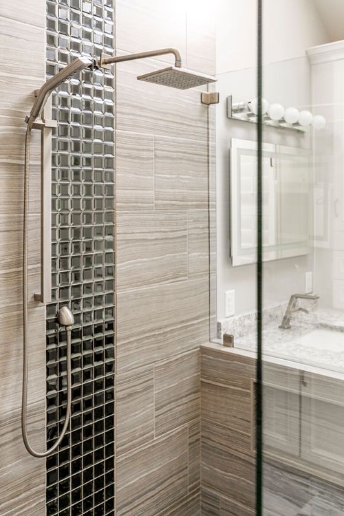 Rainfall shower head with mosaic tile surround and vanity mirror beyond