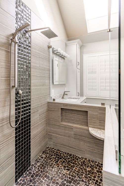 Close view of a rainfall shower head set into a mosaic glass tile column