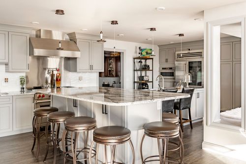 Kitchen with floor-to-ceiling gray cabinetry, a stainless fridge and wine cooler, and pendant lighting