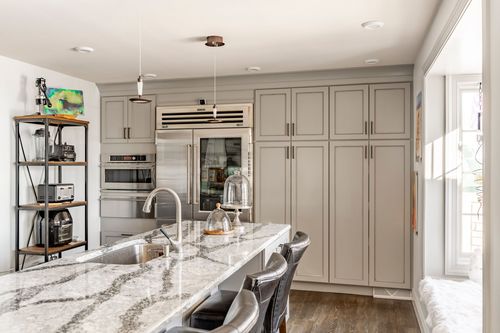 Kitchen island with a marble countertop, gray cabinetry and a bay window breakfast nook