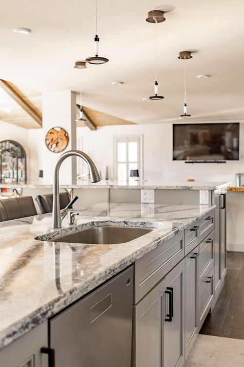 Kitchen island with quartz waterfall counter, pendant lighting and a wall-mounted TV