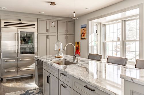 Gray kitchen with stainless refrigerator, marble island and a bay window breakfast nook