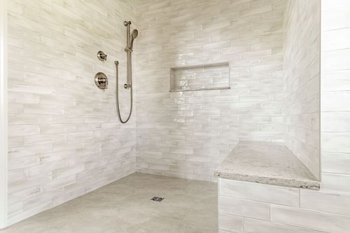 Walk-in tile shower with handheld sprayer, built-in niche and stone bench