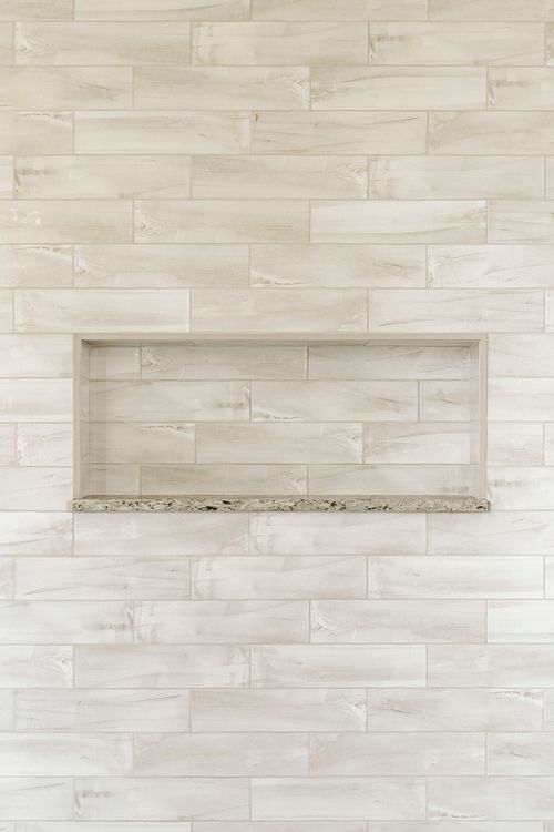 Shower wall with wood-look plank tile and a built-in storage niche