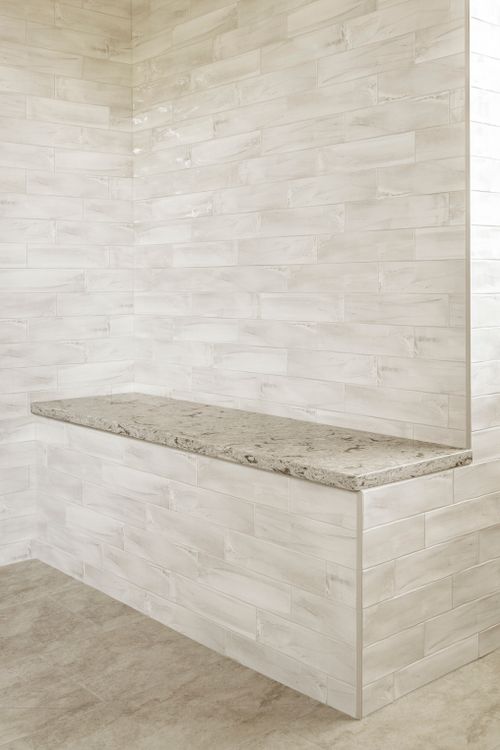 Shower bench with granite seat set into wood-look plank tile walls