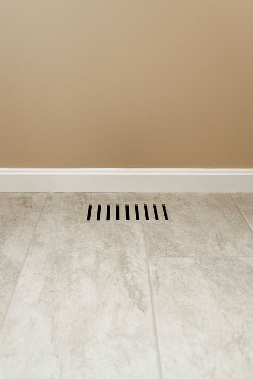 Close-up of a floor vent set into gray stone-look tile