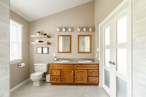 Bathroom double vanity with oak cabinets, floating shelves and vaulted ceiling