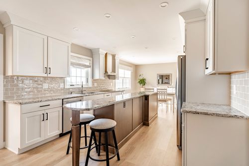 Kitchen with white cabinetry, subway tile backsplash and a dark wood island with stools