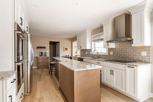 Kitchen with stainless range hood, subway tile backsplash and granite counters