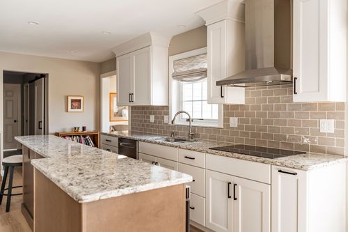 Kitchen with white cabinetry, granite counters and a window over the farmhouse sink