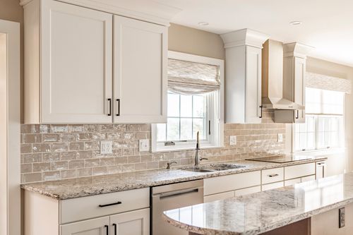 White kitchen with subway tile backsplash, stainless range hood and window over the sink