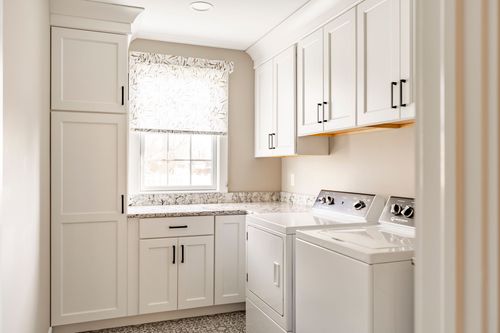 Laundry room with white cabinetry and top-load washer and dryer on patterned tile