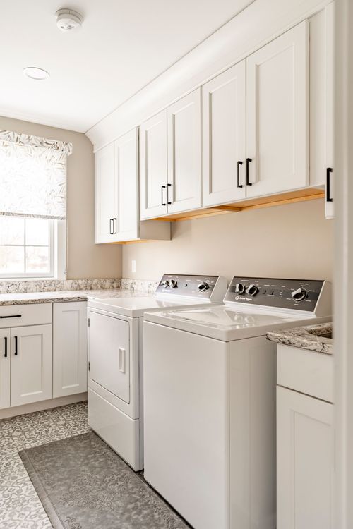 Laundry room with white upper cabinets and top-load washer and dryer set