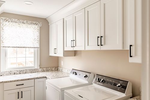 Laundry room with white cabinetry, granite counter and side-by-side washer and dryer