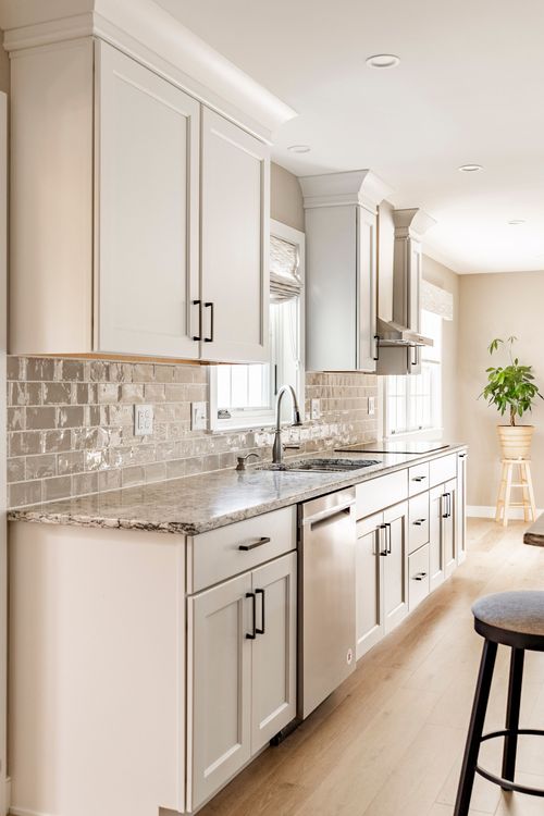 White kitchen with subway tile backsplash, granite counters and stainless dishwasher