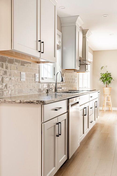White kitchen with subway tile backsplash, granite counters and a potted plant accent