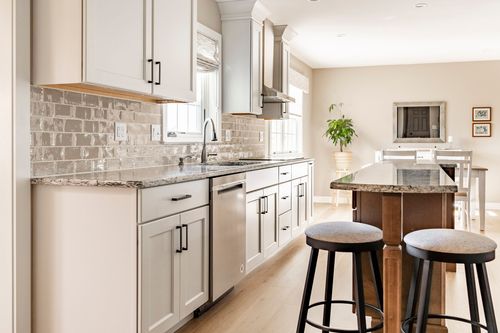 Kitchen with granite counters, subway tile backsplash and bar stool seating near the dining area