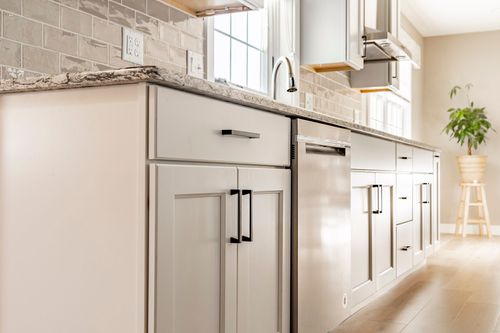 Kitchen counter with granite surface, subway tile backsplash and stainless dishwasher